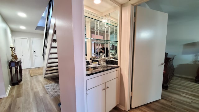 bar with light wood-type flooring and white cabinets