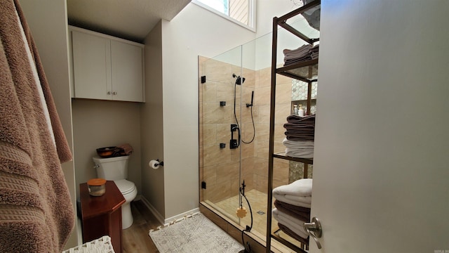 bathroom with hardwood / wood-style flooring, toilet, and a shower with shower door