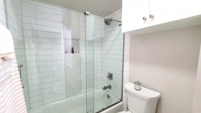 bathroom featuring toilet and bath / shower combo with glass door