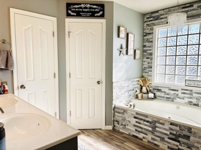 bathroom with vanity, hardwood / wood-style floors, and a relaxing tiled tub