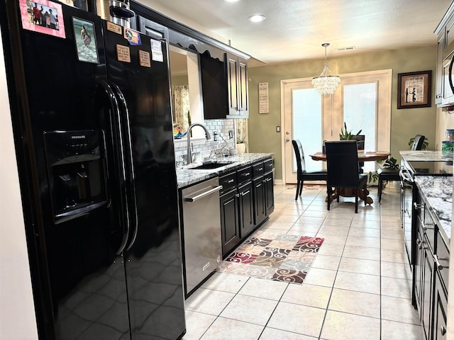 kitchen with hanging light fixtures, light stone countertops, sink, and black appliances