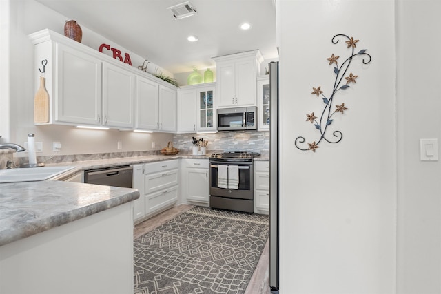 kitchen featuring stainless steel appliances, white cabinetry, sink, and backsplash