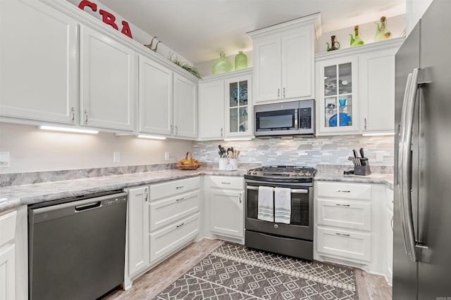 kitchen featuring light stone countertops, light hardwood / wood-style flooring, stainless steel appliances, and white cabinets