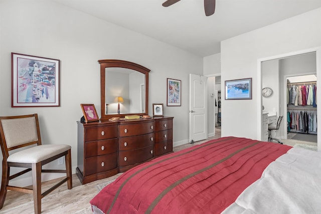 bedroom with a spacious closet, light hardwood / wood-style flooring, a closet, and ceiling fan