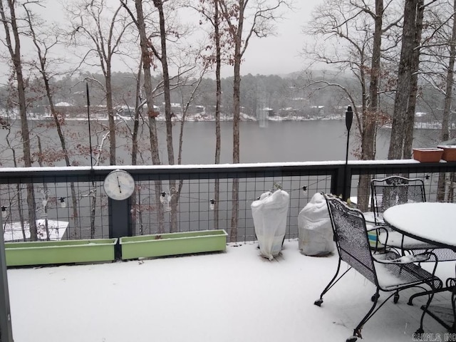 snow covered back of property featuring a water view