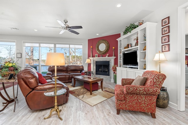 living room with light hardwood / wood-style flooring, a tile fireplace, and ceiling fan