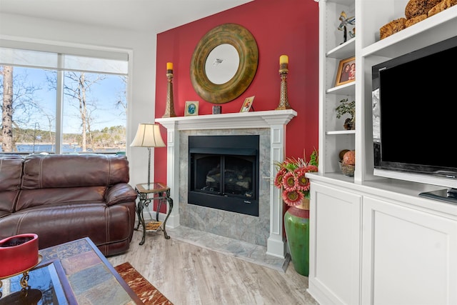 living room featuring a high end fireplace, built in features, and light wood-type flooring