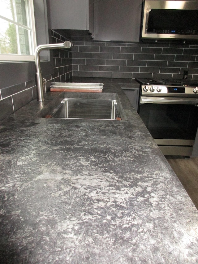 details featuring appliances with stainless steel finishes, sink, and decorative backsplash