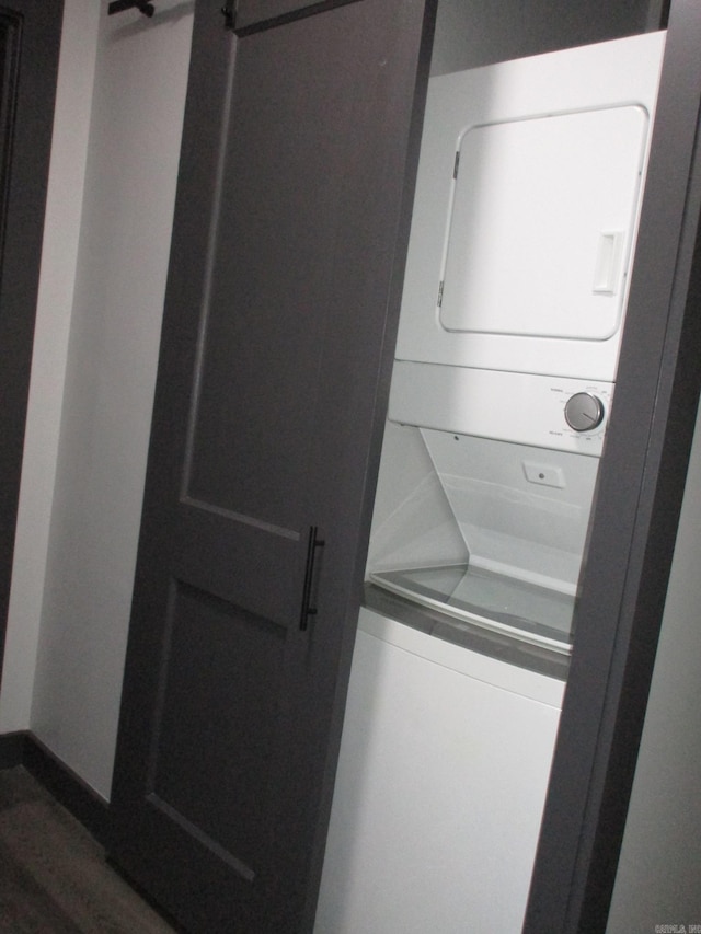 laundry room featuring stacked washer and dryer and dark hardwood / wood-style floors