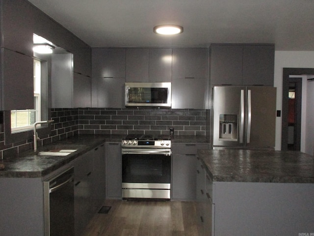 kitchen featuring sink, tasteful backsplash, dark hardwood / wood-style floors, gray cabinets, and stainless steel appliances