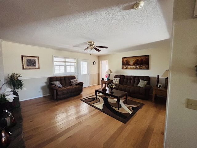 living room with hardwood / wood-style floors, a textured ceiling, and ceiling fan