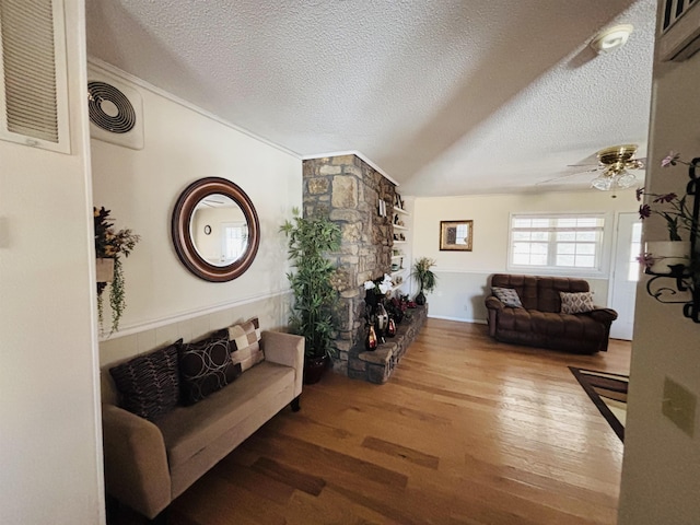 living room featuring ceiling fan, wood-type flooring, a fireplace, and a textured ceiling