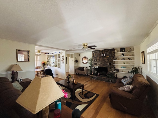 living room featuring hardwood / wood-style flooring, ceiling fan, a fireplace, and built in features