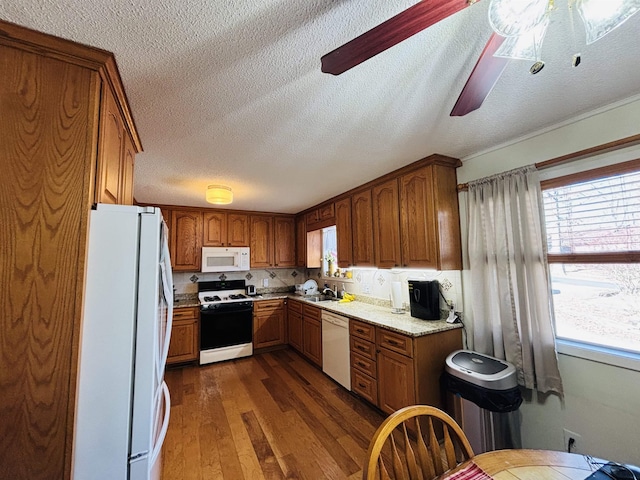 kitchen featuring dark hardwood / wood-style flooring, white appliances, a wealth of natural light, and light stone countertops