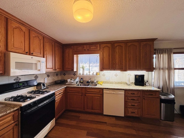 kitchen with dark hardwood / wood-style floors, sink, light stone counters, and white appliances