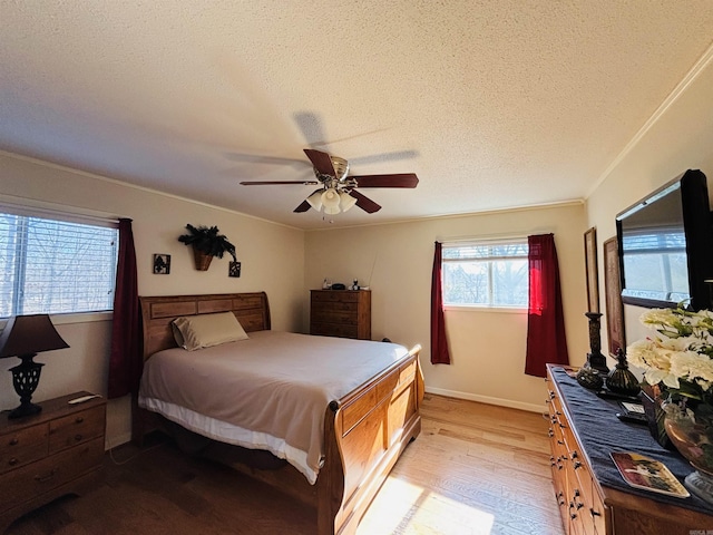 bedroom featuring crown molding, a textured ceiling, ceiling fan, and light wood-type flooring