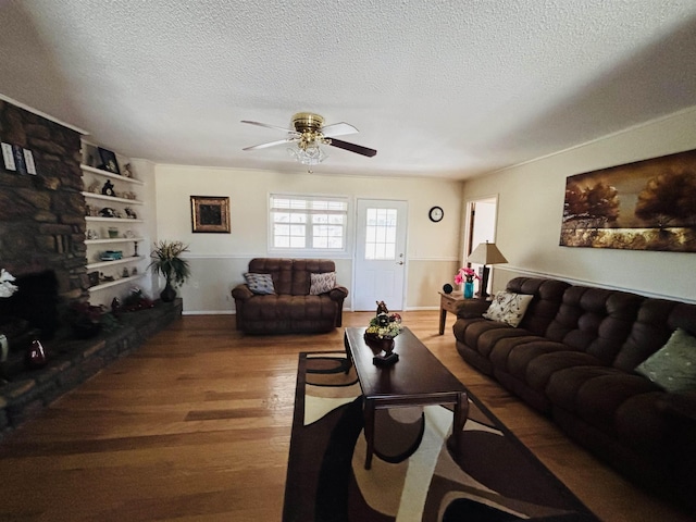 living room featuring hardwood / wood-style flooring, built in features, a textured ceiling, and a fireplace