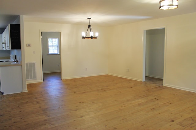 unfurnished dining area with an inviting chandelier and light hardwood / wood-style floors