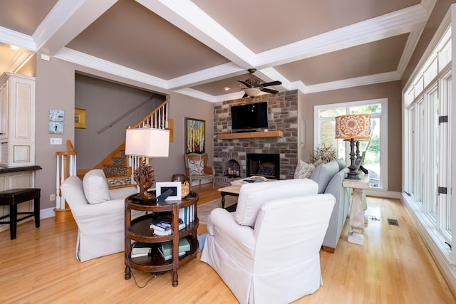 living room featuring coffered ceiling, a stone fireplace, beamed ceiling, and light wood-type flooring