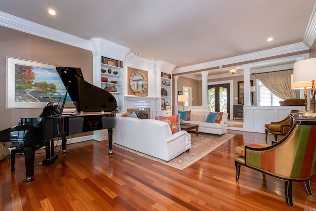 living room with hardwood / wood-style flooring, ornamental molding, decorative columns, and built in features