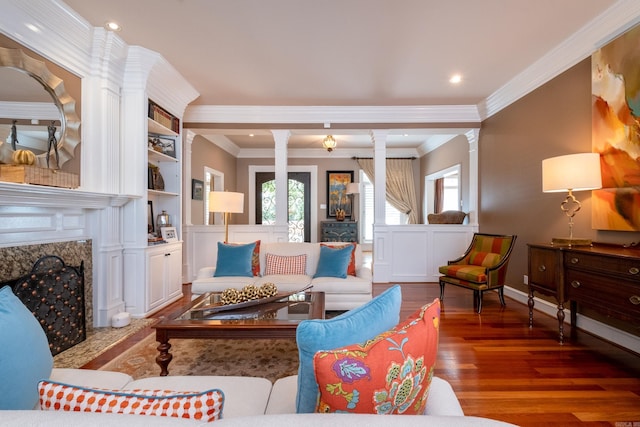 living room with crown molding, a high end fireplace, dark hardwood / wood-style floors, and ornate columns