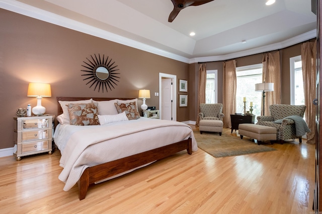 bedroom with crown molding, light hardwood / wood-style floors, a raised ceiling, and ceiling fan