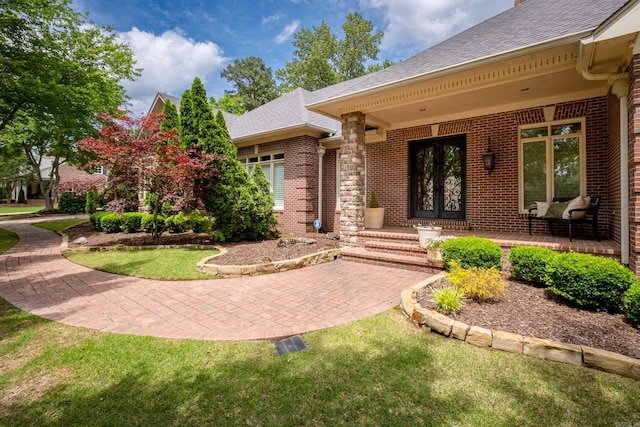 view of exterior entry featuring a yard and covered porch