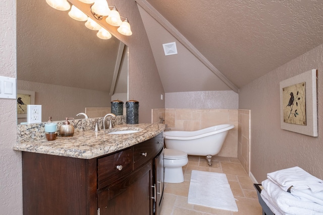 bathroom featuring lofted ceiling, a textured ceiling, vanity, tile patterned flooring, and a washtub