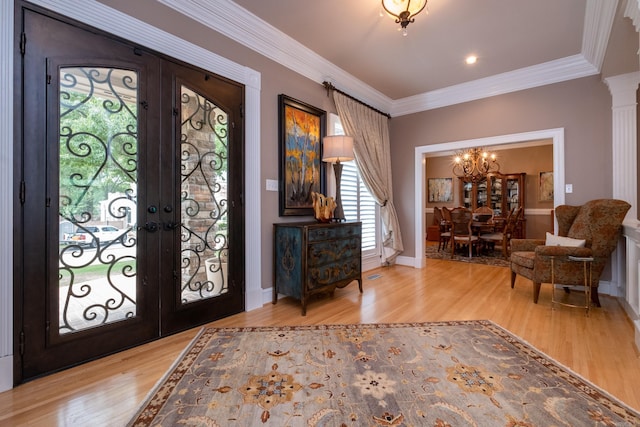 entryway with crown molding, a chandelier, light wood-type flooring, and french doors