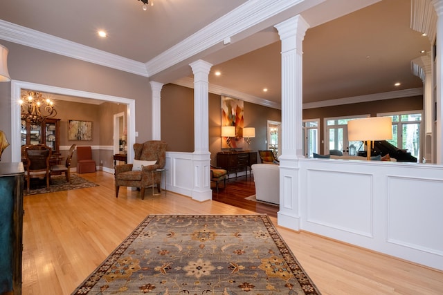 living room featuring decorative columns, crown molding, and light wood-type flooring