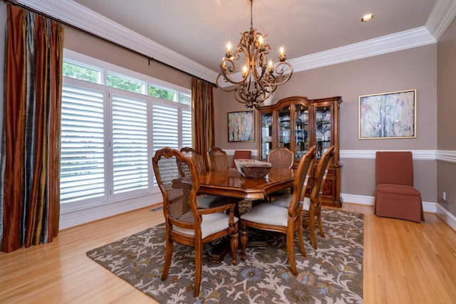 dining room with crown molding, an inviting chandelier, and light hardwood / wood-style floors