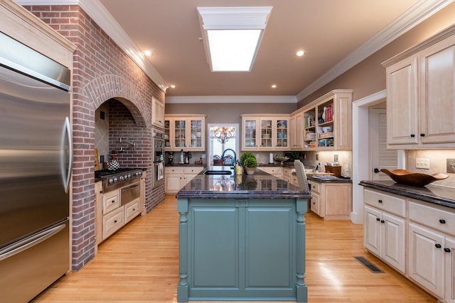 kitchen with sink, crown molding, built in refrigerator, a kitchen island with sink, and backsplash