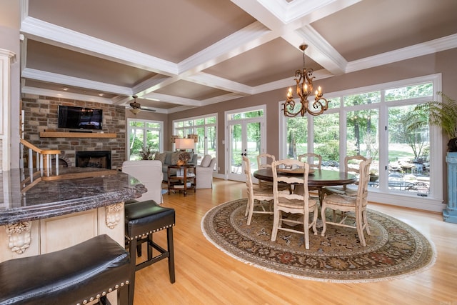 dining area featuring crown molding, light hardwood / wood-style flooring, beam ceiling, coffered ceiling, and a fireplace