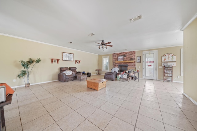 living room featuring crown molding, ceiling fan, a brick fireplace, and light tile patterned floors