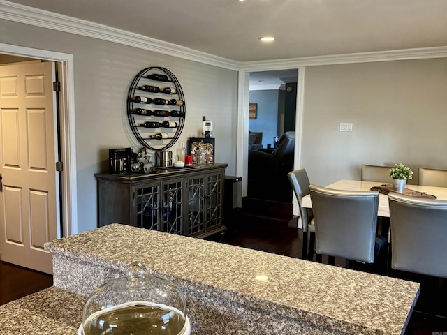 dining space with ornamental molding, bar, and dark hardwood / wood-style flooring