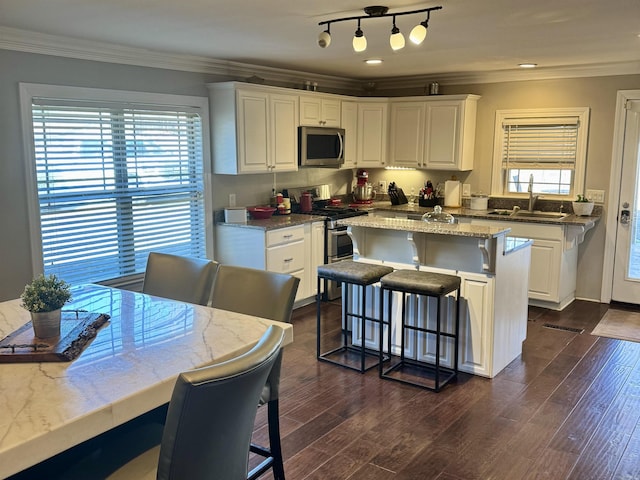 kitchen featuring white cabinetry, appliances with stainless steel finishes, a kitchen breakfast bar, and sink