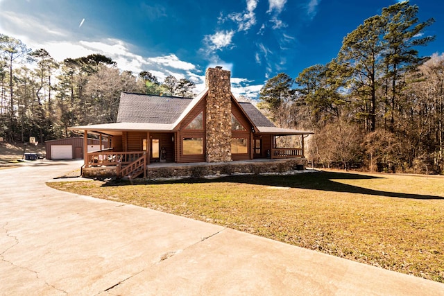 view of front facade featuring an outbuilding, a garage, covered porch, and a front yard