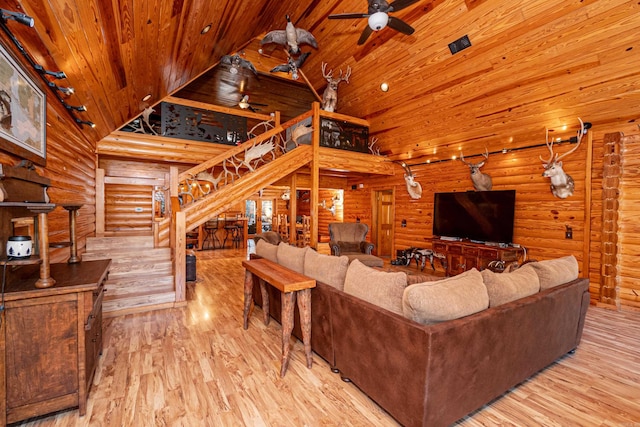 living room featuring log walls, high vaulted ceiling, and light wood-type flooring