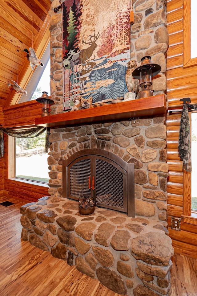 details featuring wood-type flooring, a stone fireplace, and rustic walls