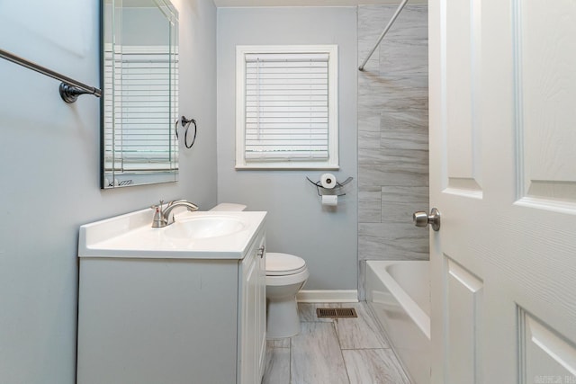 full bathroom featuring tiled shower / bath combo, vanity, and toilet