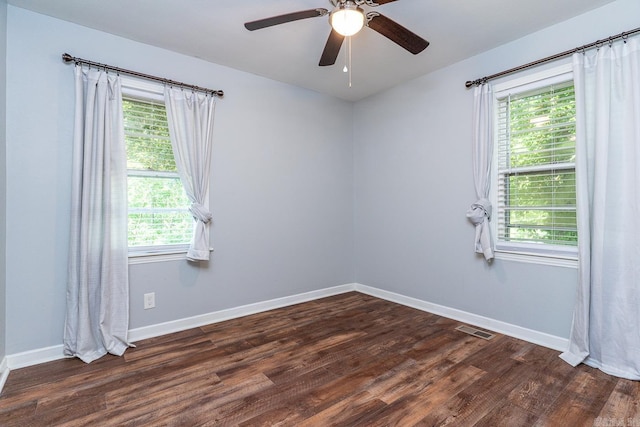 empty room with dark wood-type flooring, a wealth of natural light, and ceiling fan