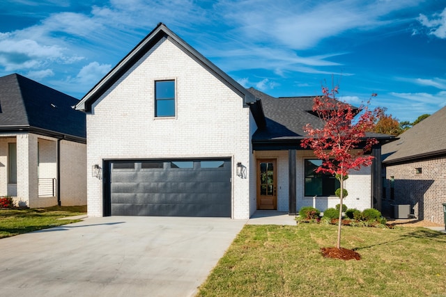 view of front of property with a garage, central AC, and a front lawn