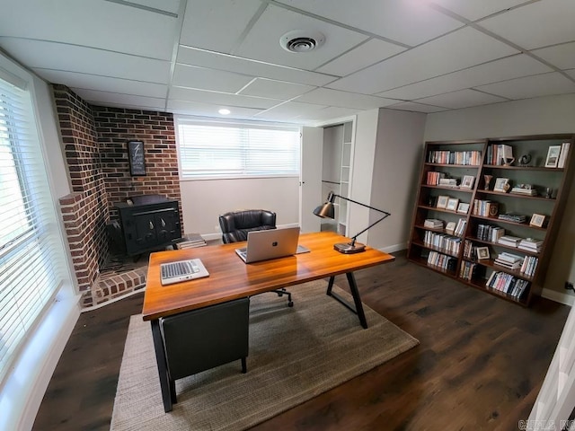 office area with a wood stove, a paneled ceiling, and dark hardwood / wood-style flooring