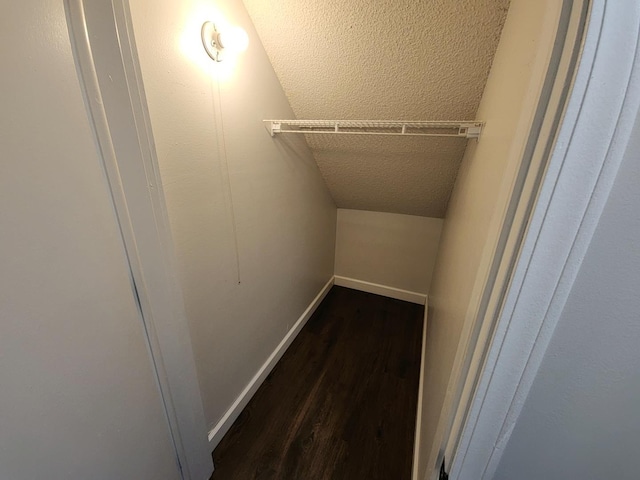 spacious closet with dark hardwood / wood-style flooring and vaulted ceiling