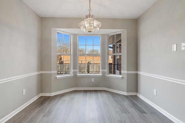 unfurnished room with hardwood / wood-style floors and a notable chandelier