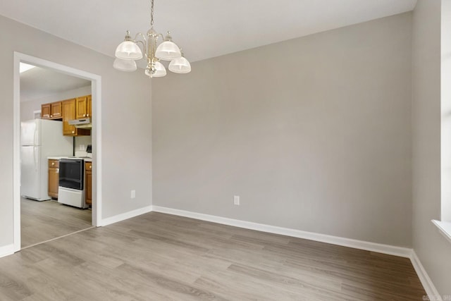 spare room featuring an inviting chandelier and light hardwood / wood-style flooring