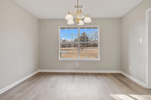 unfurnished dining area featuring light wood-type flooring and a chandelier