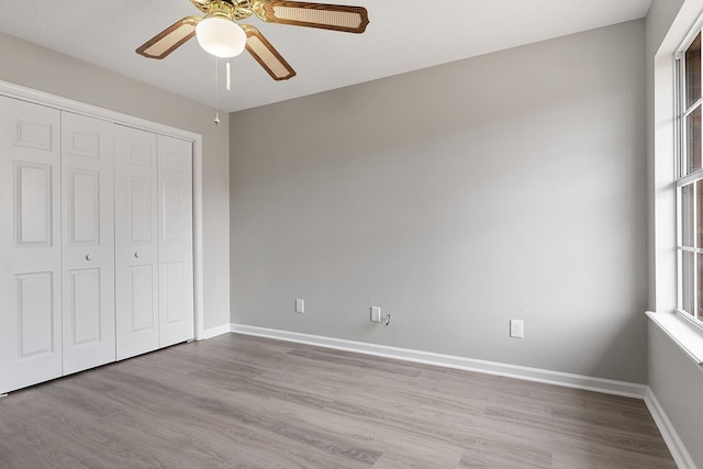 unfurnished bedroom with ceiling fan, a closet, and light hardwood / wood-style flooring