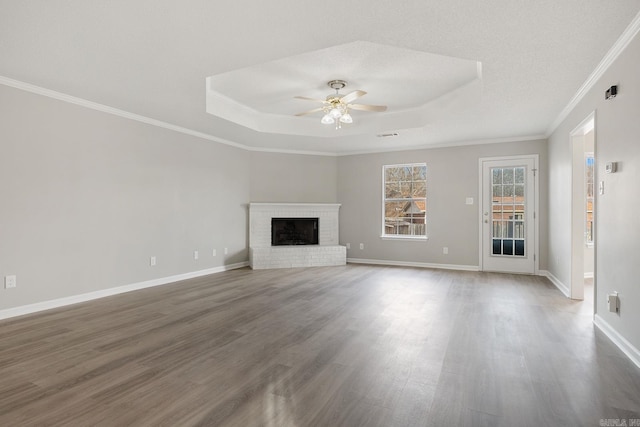 unfurnished living room with hardwood / wood-style flooring, ceiling fan, a fireplace, and a raised ceiling