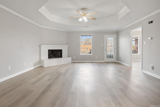 unfurnished living room featuring ornamental molding, ceiling fan, a fireplace, and a tray ceiling